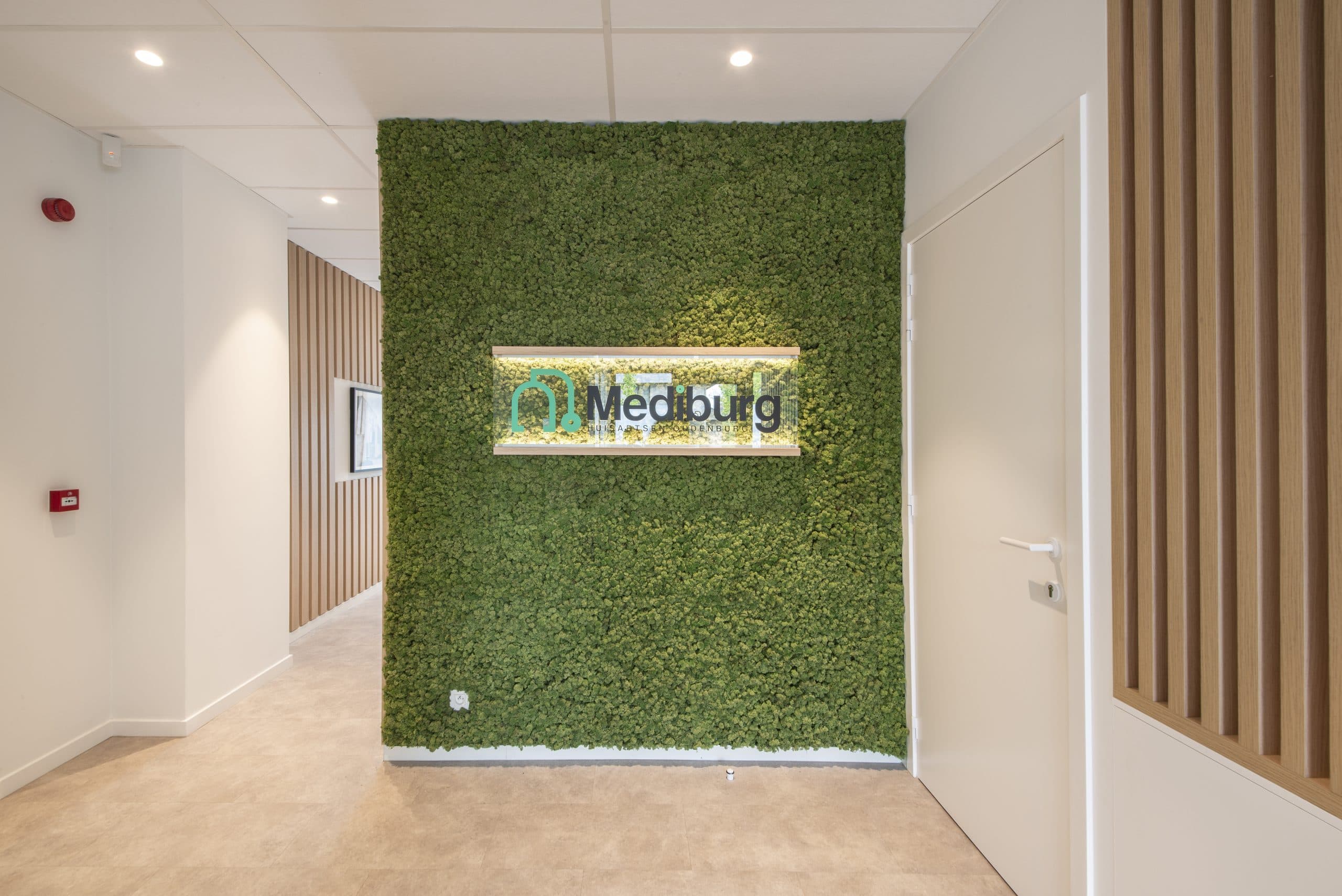 Un mur en gazon artificiel avec une vitrine en verre portant le logo de Medburg.